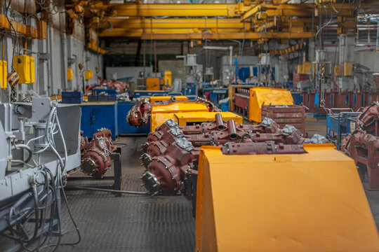 Industrial interior of tractor manufacturing plant with tractor parts on assembly line. Atmosphere of heavy machinery factory. Industrial production, engineering, manufacturing processes.