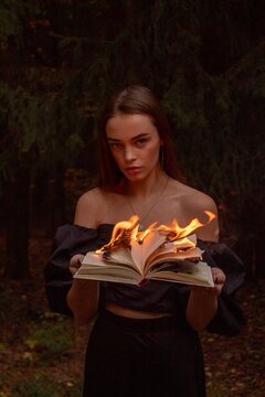 Gothic Woman Holding a Burning Book in the Forest