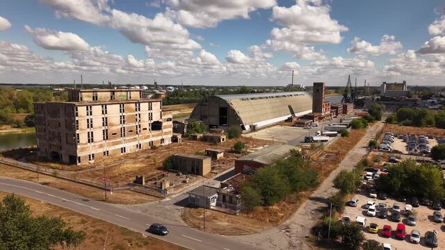 Wide drone view of abandoned oval factory building and cityscape