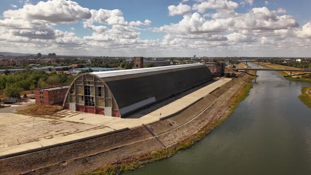 Wide aerial view of abandoned oval building under dramatic clouds