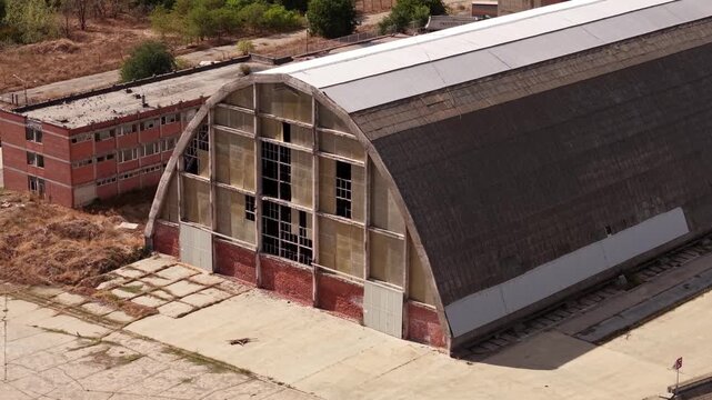 Close drone view of arched factory facade and broken windows