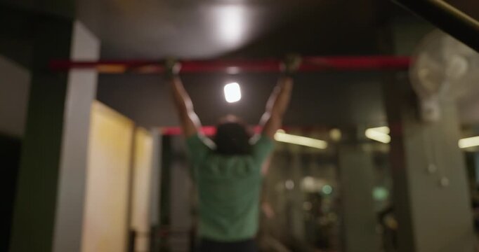 An Indian male athlete performs strict pull-ups on a pull-up bar in a modern gym. He uses controlled bodyweight movements to build back, shoulder, and arm strength
