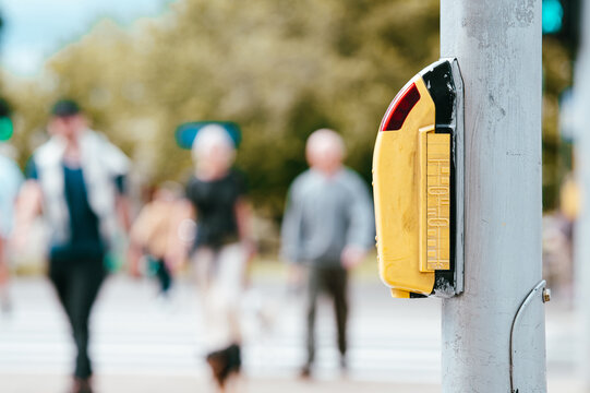 Yellow button to request a walk signal for pedestrians crossing at a busy city intersection