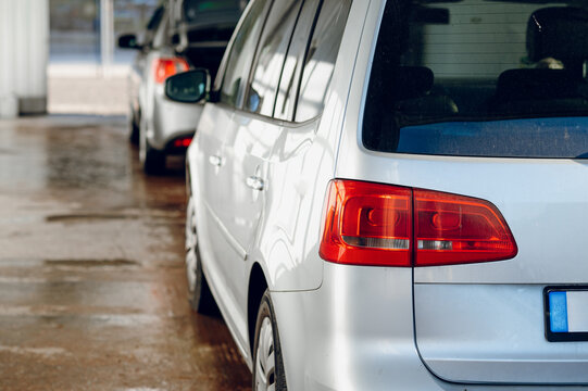 Rows of silver vehicles parked on a wet floor while undergoing cleaning at a professional center