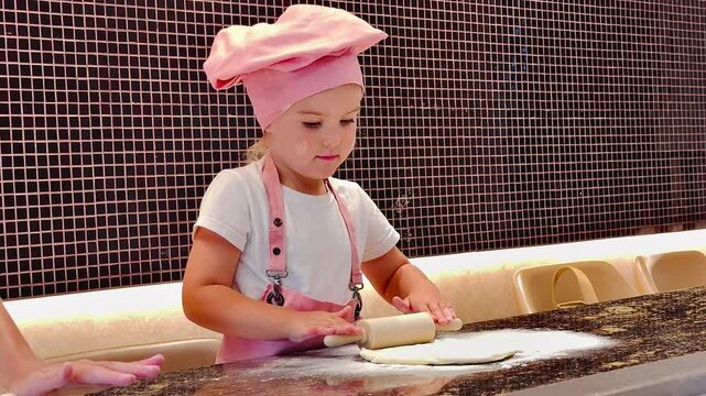 Little chef rolling pizza dough with a small rolling pin &mdash; kids cooking