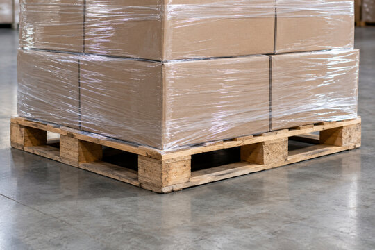 Stretch film securing the bottom layer of cartons to a wooden pallet