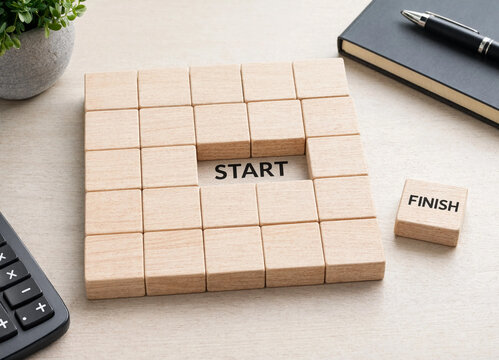 Wooden blocks arranged in a square with start and finish text on a table