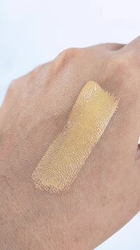 Point of view of applying cushion foundation on hand skin using a mini brush. Makeup try on concept, cosmetic product test for beauty routine.