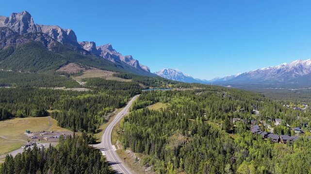 Highway 742 Three Sisters Pkwy or Spray Lakes Road through autumn pine forest and mountains aerial view. Canmore, Alberta, Canada.