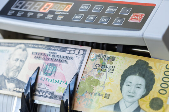 USD and KRW banknotes inside counting machine. Economic concept of South Korean won and US dollar exchange rate, forex trading, asian market finance and global valuation. Close-up.