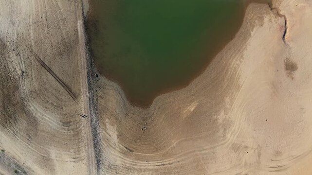 Aerial view of a drying reservoir with receded water levels exposing arid, cracked soil due to extreme drought and climate change