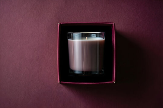 Plain hand-poured candle in a smoked-glass vessel inside an open rigid box for premium winter gifting, luxury retail and holiday packaging campaign