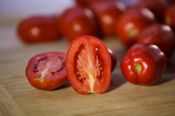 Fresh ripe sliced red tomatoes on a rustic wooden cutting board with copy space © Denis