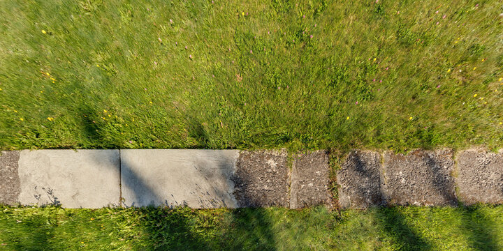 view from above on texture of gravel road among grass field