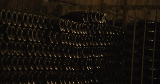 Closeup of working hands with bottles. Top down view of workers handling glass bottles carefully. Precise placement of dark glass bottles by gloved hands in cellar storage