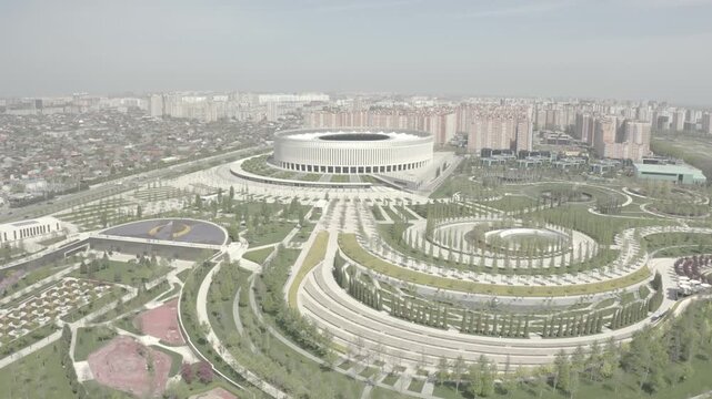 Aerial panorama of circular urban plaza with concentric tree rings and central ponds under overcast daylight emphasizing geometric symmetry and landscape layout