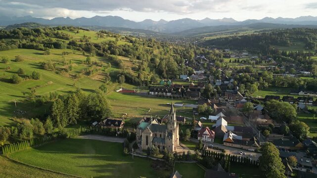 Chochoł&oacute;w - Polska 
Piękny kości&oacute;ł na tle Tatr Zachodnich nagany dronem. Ujęcia płynne i kinowe o dobrej jakości, kości&oacute;ł, g&oacute;ry, Tatry, Podhale, drzew, nieb, chmury
