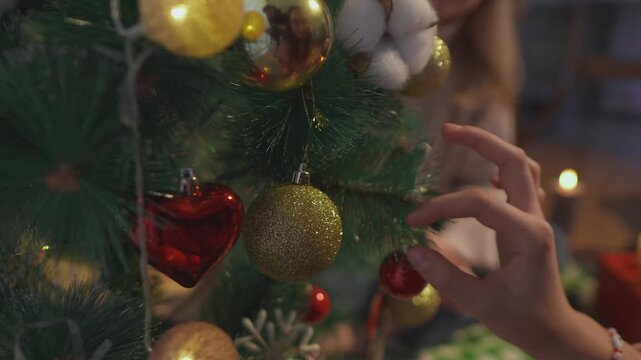 Warm seasonal footage focuses on hands that adjust round ornaments on a Christmas tree with careful fingertips. Macro hand view conveys festive attention to detail in a polished lifestyle scene.