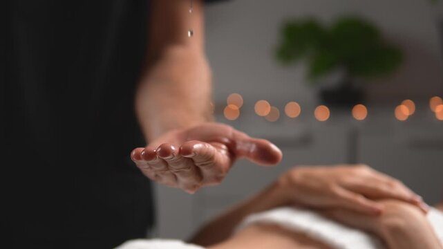 Video captures a massage therapist who prepares his hands for a soothing body massage beside a relaxed client. The scene conveys massage preparation, professional care and body care.