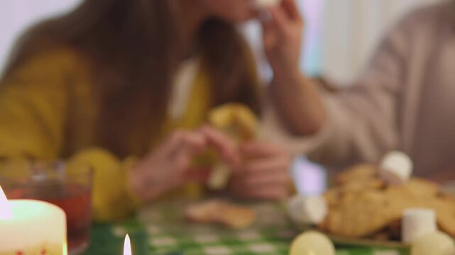 Close footage shows female hands that decorate homemade Christmas cookies beside warm candles and golden ornaments. Close detail view highlights festive baking tradition through warm seasonal detail.