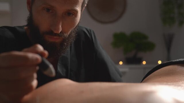 Video captures a massage therapist who prepares and handles acupuncture needles beside a resting client. The scene conveys clinical hygiene, professional practice and body care.