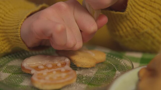 Two female friends smell and inspect freshly prepared holiday cookies at the table. Low close view highlights sensory food experience through warm seasonal detail for advertising.