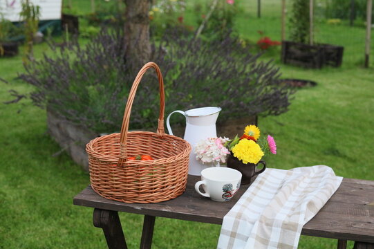Cozy autumn garden still life with a wicker basket notebooks blue jug and cup on a rustic wooden table outdoors