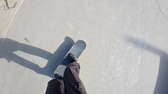 A skateboarder is missing a trick in POV and falling on the ground in a skatepark on a sunny day, super slow motion