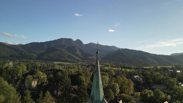 Zakopane - Polska
Widok na kości&oacute;ł, Tatry, Giewont nagrany dronem w słoneczny dzień. Piękne widoki g&oacute;rskie nagrane z powietrza w stolicy Podhala