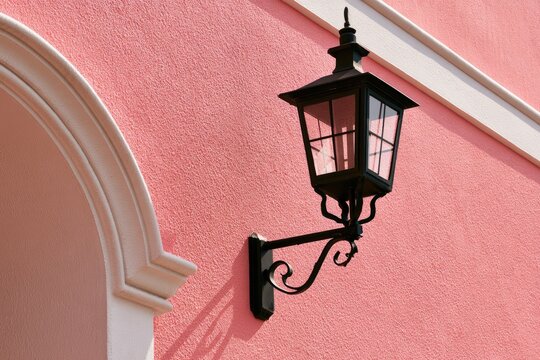 Ornate black lantern mounted on textured pink wall with white architectural trim