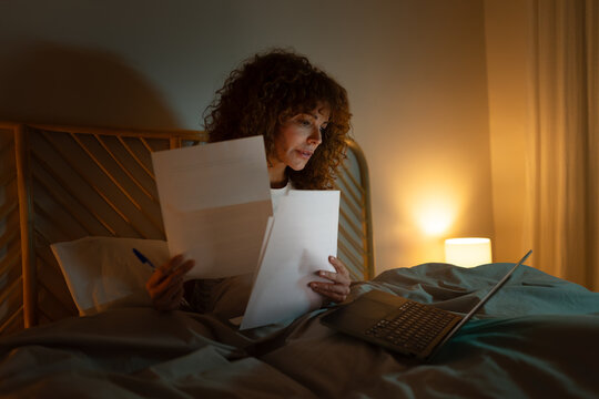 Woman reviewing documents and working late in bed