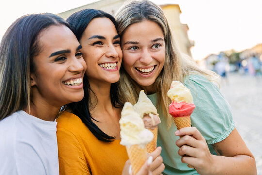 Female friends enjoying ice cream together outdoors. Young women sharing sweet moments during summer vacation. Lifestyle and leisure concept.