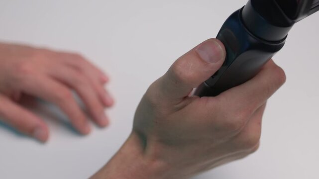 Person adjusts camera stabilizer while smiling in professional studio setup. Person in casual attire is testing camera movement techniques in blue studio environment