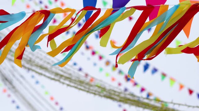 Bright red, yellow, and blue streamers flutter diagonally against a soft sky, creating a festive mood. Traditional Maslenitsa festivities	
