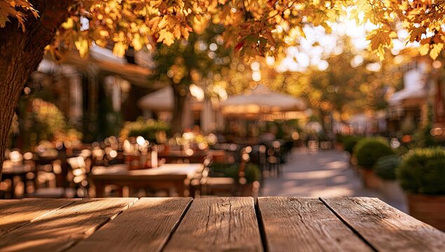 Empty wooden table bathed in warm autumn sunlight at an outdoor cafe