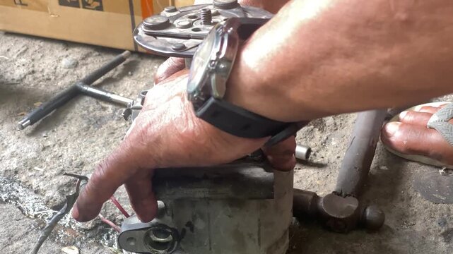 technician is assembling pieces of a broken car air conditioning compressor on the pavement.