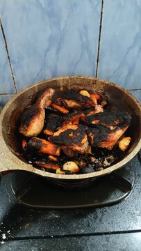 Burnt chicken in frying pan on stove, overcooked charred poultry pieces, kitchen cooking mistake and ruined meal
