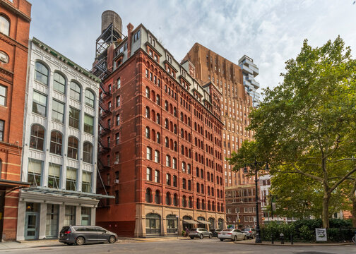 New York, NY - US - Sep 25, 2026 : Historic brick and cast-iron buildings near Staple Street in Tribeca rise beside Duane Park, with arched windows, rooftop water tower and mature trees in Manhattan.
