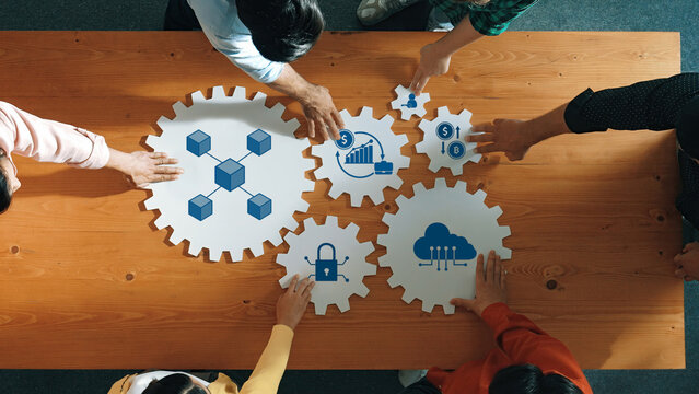 A vibrant teamwork scene showcasing diverse individuals collaborating over puzzle-like gears on a wooden table, symbolizing innovation and strategic planning in business. Amity