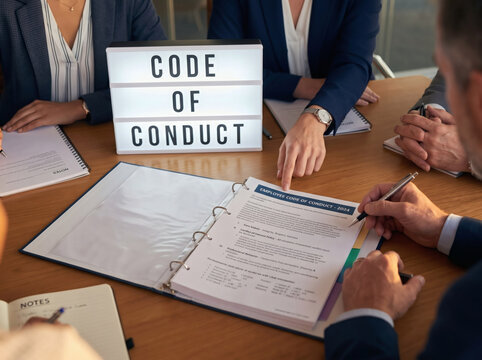 professional business meeting reviewing code of conduct document on table leadership team ethics board meeting in bright office with golden hour lighting corporate compliance