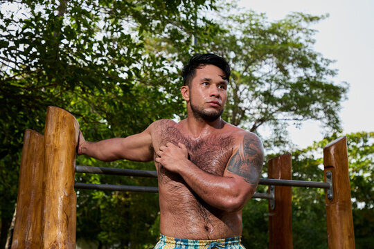 Man doing calisthenics workout and pull-ups on parallel bars in a public park