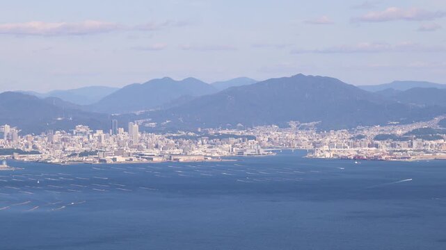 Hiroshima City aerial panoramic view seen from Mount Misen on Miyajima Island, with Seto Inland Sea, Hiroshuma bay and skyline, port and oyster farming rafts, Chugoku, Japan, mountains in background