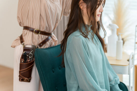 Long-Haired Woman Receiving a Hair Treatment from a Hairstylist Wearing a Scissor Holster at a Hair Salon