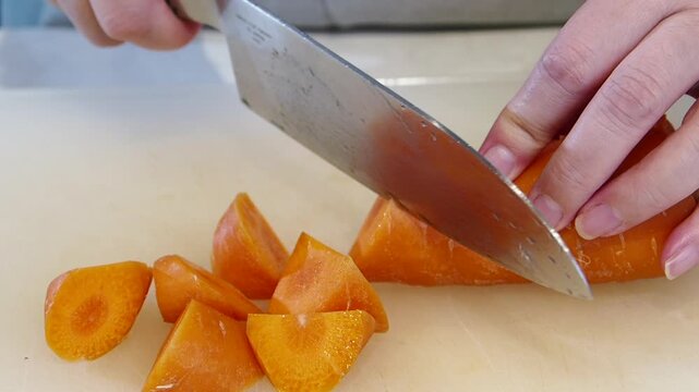 ハイスピード撮影した女性主婦がキッチンで包丁で人参を切る様子