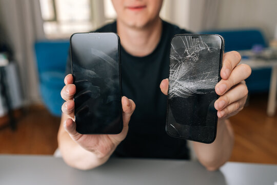 Man holding two smartphones, showing repaired device with clean screen and damaged phone with cracked display, illustrating successful repair service, close-up, cropped shot