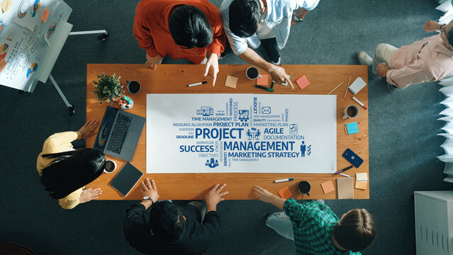 Engaging aerial view of a diverse team collaborating on project management strategies in a modern workspace. Focus on planning and effective team dynamics for business success. Amity