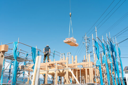 新築木造住宅の上棟。クレーンで木材を吊り上げる建方作業中の建築現場