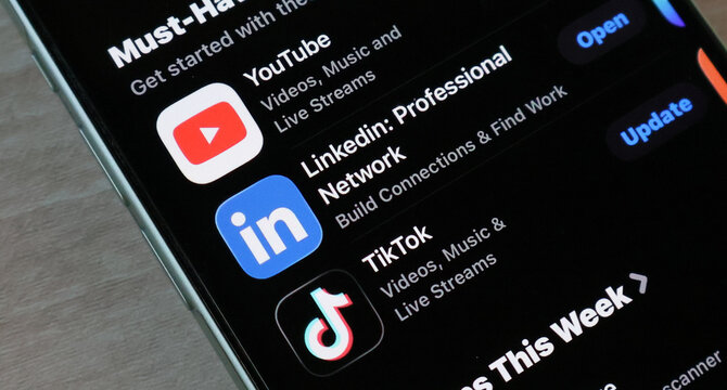 Angled view of smartphone displaying popular app store recommendations on dark mode interface.