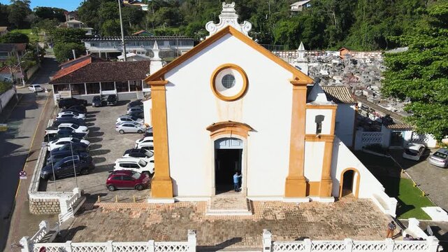 Aerial drone shot of the historic facade of Nossa Senhora das Necessidades church and colonial square in Santo Antonio de Lisboa village, Florianopolis, Santa Catarina, Brazil.
