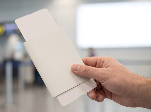 Hand Holding White Envelope with Partially Open Flap at Airport Check-in Counter Soft Diffused Lighting Close-up View with Copy Space for Travel Ticketing Advertising